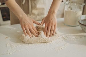 une personne pétrit la pate a pinsa sur une table