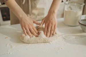 une personne pétrit la pate a pinsa sur une table